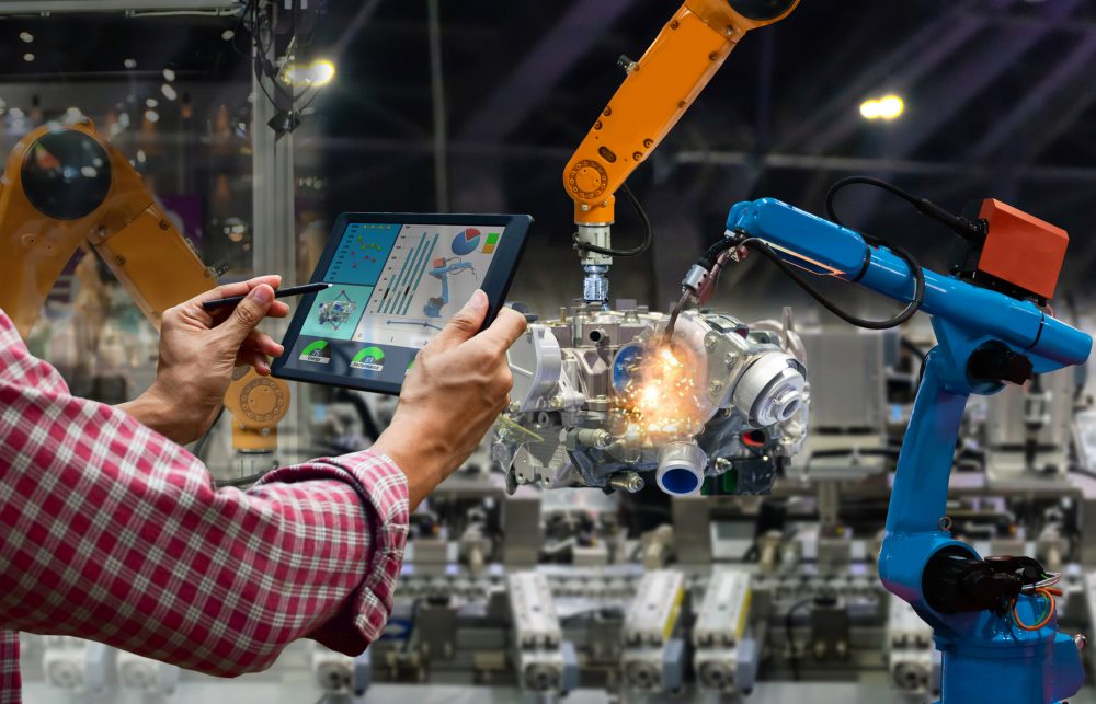 Człowiek trzyma tablet umożliwiający zarządzanie robotami spawalniczymi