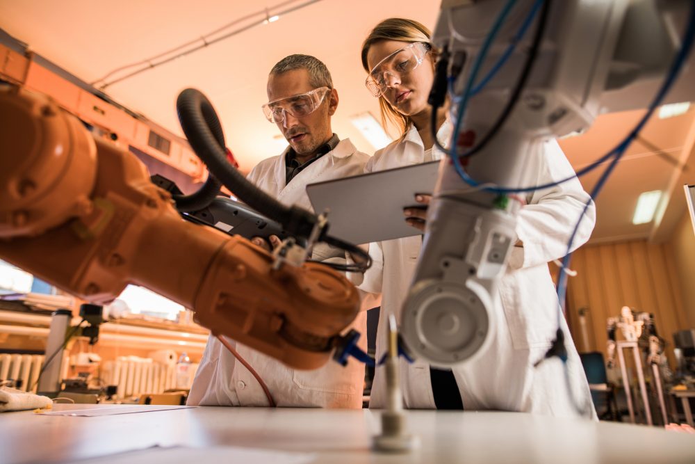 widok naukowców współpracujących przy pracy nad robotycznym ramieniem w laboratorium.