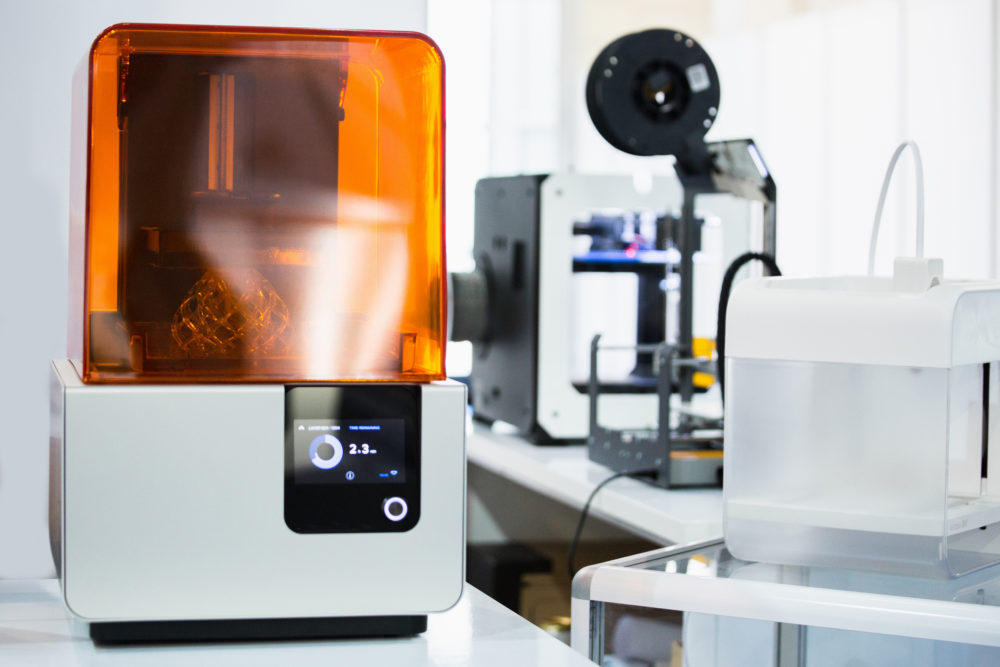 A stereolithography 3d printer in the laboratory prints a structure from a photopolymer. Creating scaled model by UV polymerization.