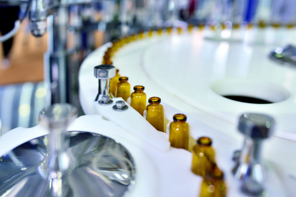 Close-up of brown glass bottle at turntable production line.