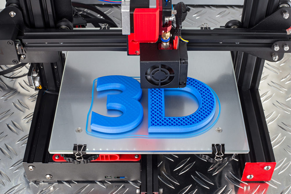 Czerwono-czarna drukarka 3D drukująca niebieski symbol logo na metalowej płycie diamentowej