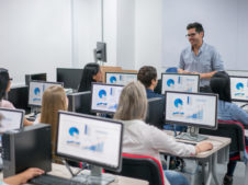 teacher giving an IT class at school to a group of students using computers - education concepts. Image on screens were made from scratch by us.